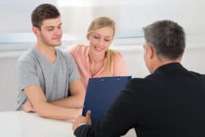 broker at desk with young couple